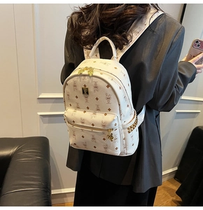Close-up of stylish cream backpack with bunny patterns and golden rivets on side pocket
