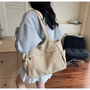 Dettaglio della borsa tote grande in tela beige con tasche laterali e spallacci robusti
