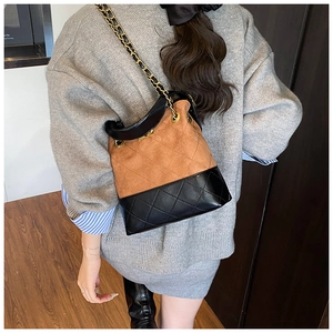 Detail of color-block quilted bucket bag with gold-tone chain strap and suede finish
