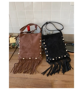 Detail of bohemian fringe bags in brown and black suede with metal rivet accents