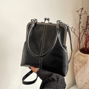 Close-up of retro black shell bag with white stitching and vintage metal clasp