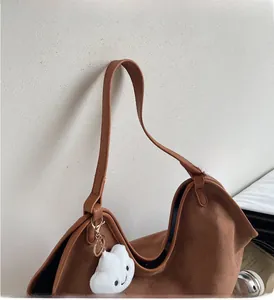 Detail of vintage brown suede tote bag with wide strap and white plush cloud charm