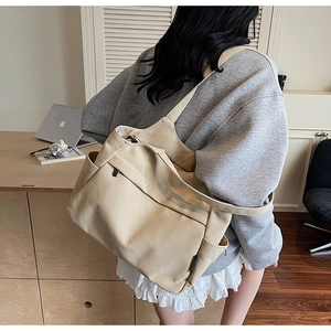 Dettaglio di una borsa tote in nylon beige con tasche laterali e cerniera frontale