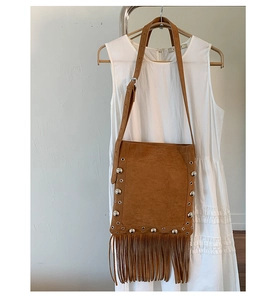Close-up of vintage brown suede shoulder bag with rivets and stylish long tassels
