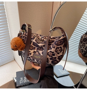 Close-up of leopard print shoulder bag with brown leather strap and plush teddy charm