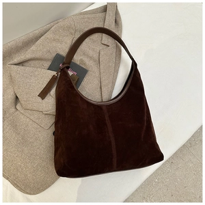 Détail du sac hobo en daim marron foncé avec poignées en cuir et étiquette décorative