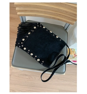 Detail of a black studded shoulder bag with fringe tassels and matte finish
