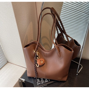 Detail view of brown PU leather tote bag with long shoulder strap and cute bear plush charm