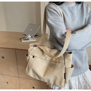 Dettaglio della borsa tote in tela beige con tracolla larga e tasca laterale extra
