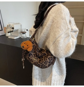 Leopard print crescent shoulder bag with dog charm and brown leather strap details