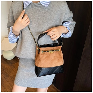 Detail view of quilted leather bucket bag with chain strap worn in a lifestyle setting