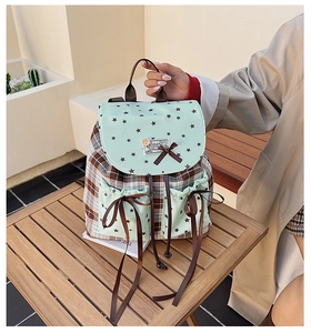 Detail of mint green backpack flap with brown bow and star pattern in plaid design