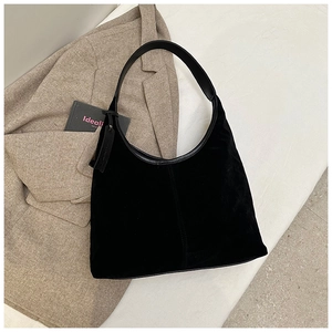 Vue détaillée du sac hobo en daim noir avec lanières en cuir sur textile beige doux