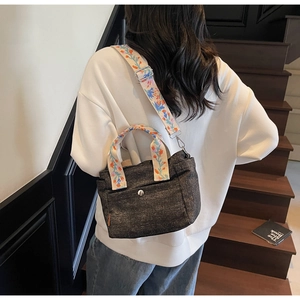 Black denim tote bag with floral embroidered straps shown from a back-view model shot