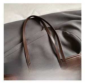 Detail der braunen karierten Tragetasche mit Kontrastnähten und Leder-Markenetikett