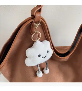 Cute white cloud plush charm with embroidered smile and striped legs on a brown tote bag