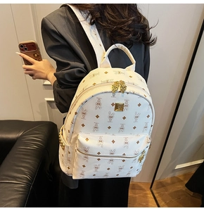 Detail view of the beige backpack featuring golden zippers and cartoon IP print textures