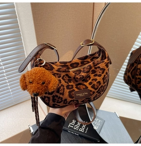 Macro detail of leopard print shoulder bag with plush dog charm and gold hardware