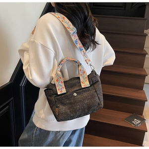 Detail of grey canvas tote bag with vibrant floral embroidery on wide shoulder strap