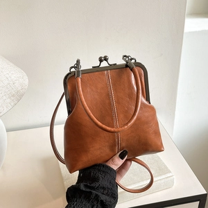 Close-up of vintage brown leather kiss-lock handbag with white stitching and bronze clasp