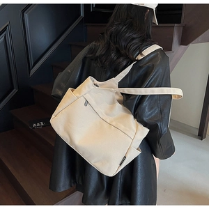 Dettaglio della borsa tote in tela beige con tasca laterale indossata a spalla