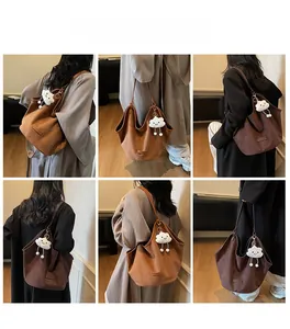Model showcasing minimalist large tote bags in caramel and dark coffee with plush charms
