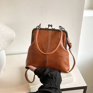 Detail of vintage caramel leather handbag with metal clasp and elegant top handle