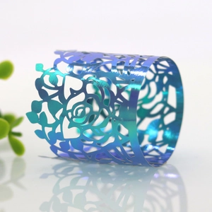 Close-up of laser-cut rose napkin ring with blue-green gradient and metallic luster