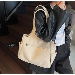 Dettaglio della borsa tote in tela beige con tasca laterale e cerniera a scomparsa