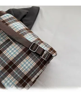 Detail of adjustable silver buckles on a brown nylon strap for a plaid backpack