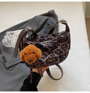 Close-up of leopard print shoulder bag with leather strap and cute plush dog charm