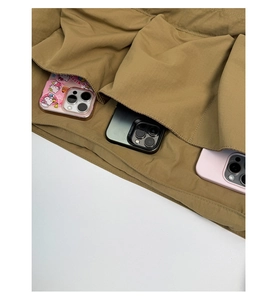 Detailansicht der drei Vordertaschen einer khakifarbenen Tragetasche mit Smartphones