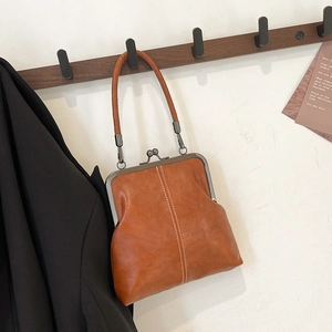 Detailed view of a vintage brown leather doctor bag hanging on a dark wood wall hook