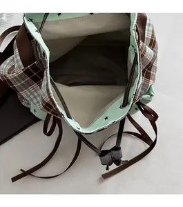 Close-up of drawstring closure on plaid backpack with star pattern inner lining