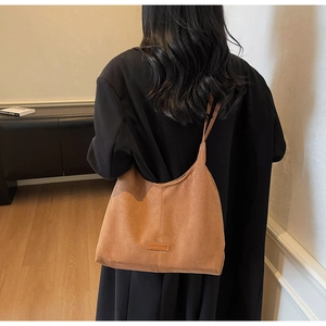 Dettaglio della borsa tote in pelle scamosciata caramello con etichetta logo rettangolare