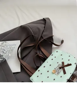 Mint green star patterned backpack with brown strap and bow shown in a cozy lifestyle setting