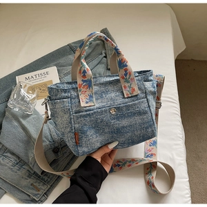 Detail of denim tote bag with colorful floral woven straps and silver button pocket