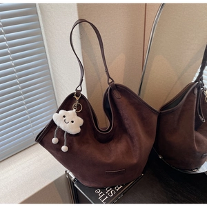Close-up of deep brown suede tote bag with a white plush cloud charm for office use