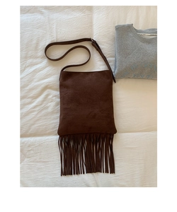 Detail shot of vintage dark brown suede shoulder bag featuring stylish long tassel fringe