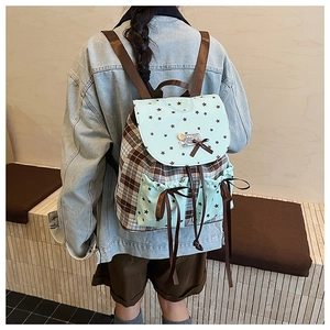 Detail of plaid student backpack with drawstring closure and wooden button on the flap