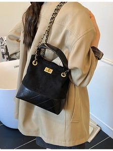 Retro black quilted bucket bag with gold chain strap worn by a model in a modern room