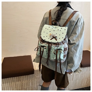 Rear view of a plaid backpack with green star patterns and brown decorative bows