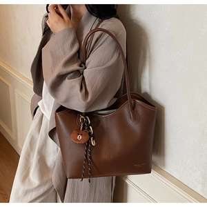 Brown leather tote bag detail with minimalist design and cute brown bear plush charm