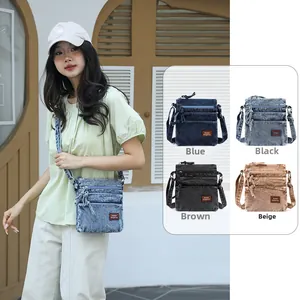 Detail of vintage denim crossbody bag with multi-layer zipper pockets and leather label
