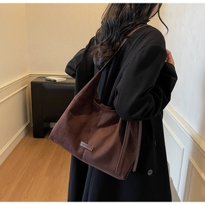 Dettaglio della borsa tote in pelle scamosciata marrone con cinghie laterali regolabili