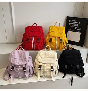 Cinco mochilas de nailon ligero en colores variados mostradas sobre escalones de mármol blanco