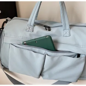 Front zipper pocket of light blue nylon travel bag holding a green tablet for storage