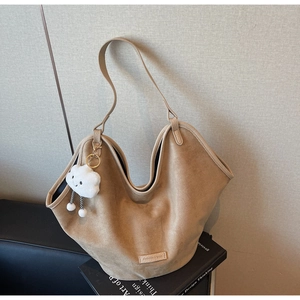Detail of light brown suede tote bag with wavy edge, brand tag and cloud charm