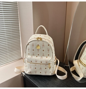 Detailed view of the white monogram backpack featuring golden zippers and decorative rivets