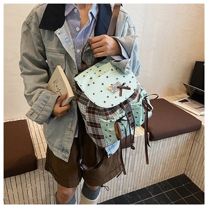 Detail view of plaid backpack featuring mint green star pattern and side drawstring pocket
